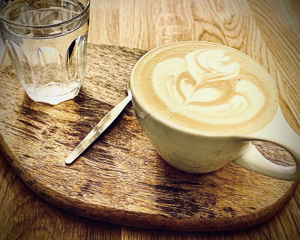Latte art rose on wooden board with a glass of water